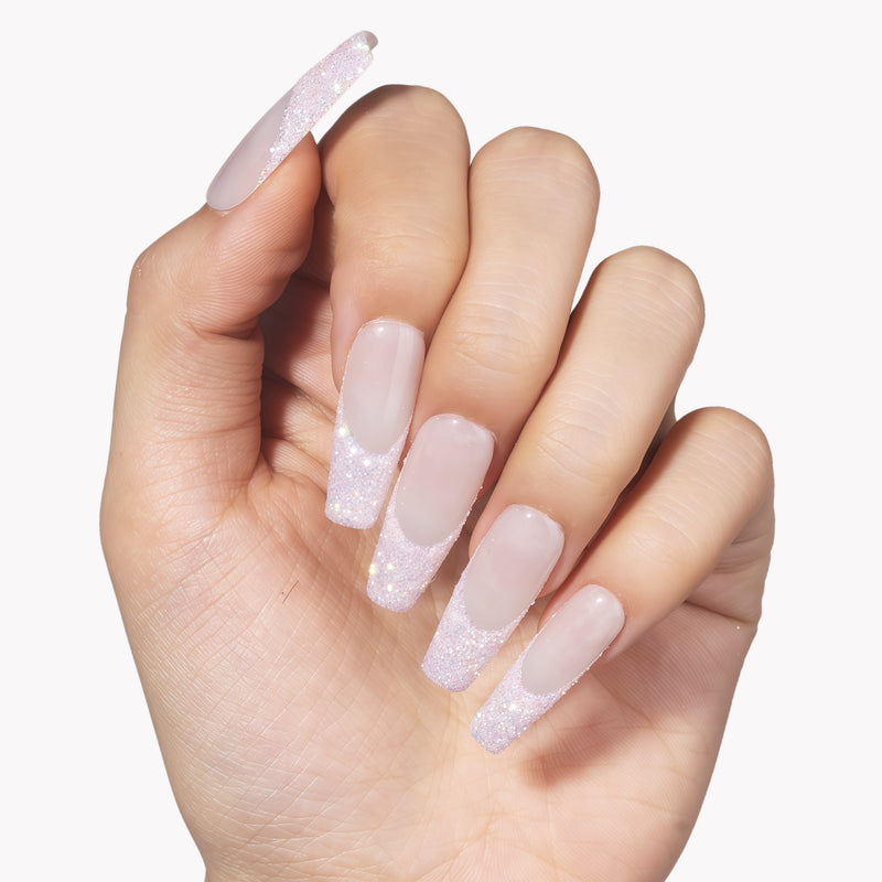 Hand model wearing Pink Confetti press-on nails with sheer nude pink square bases and sparkling pink silver glitter French tips