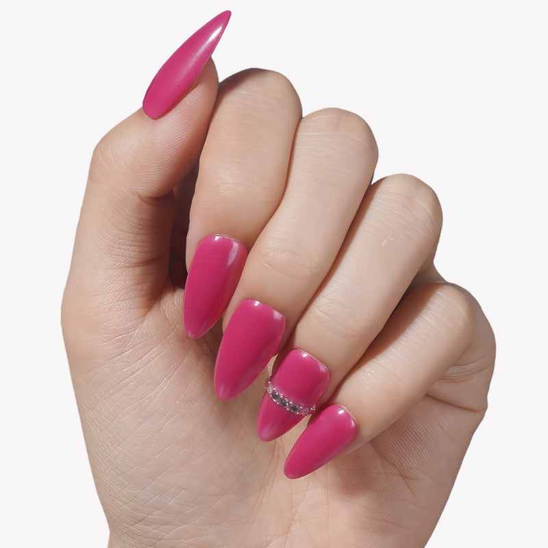 Close-up of a hand wearing glossy hot pink press-on nails with a crystal accent.