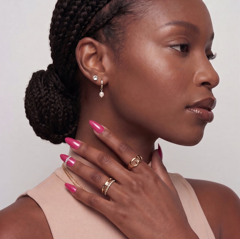 Hand model wearing glossy hot pink press-on nails with a crystal accent.