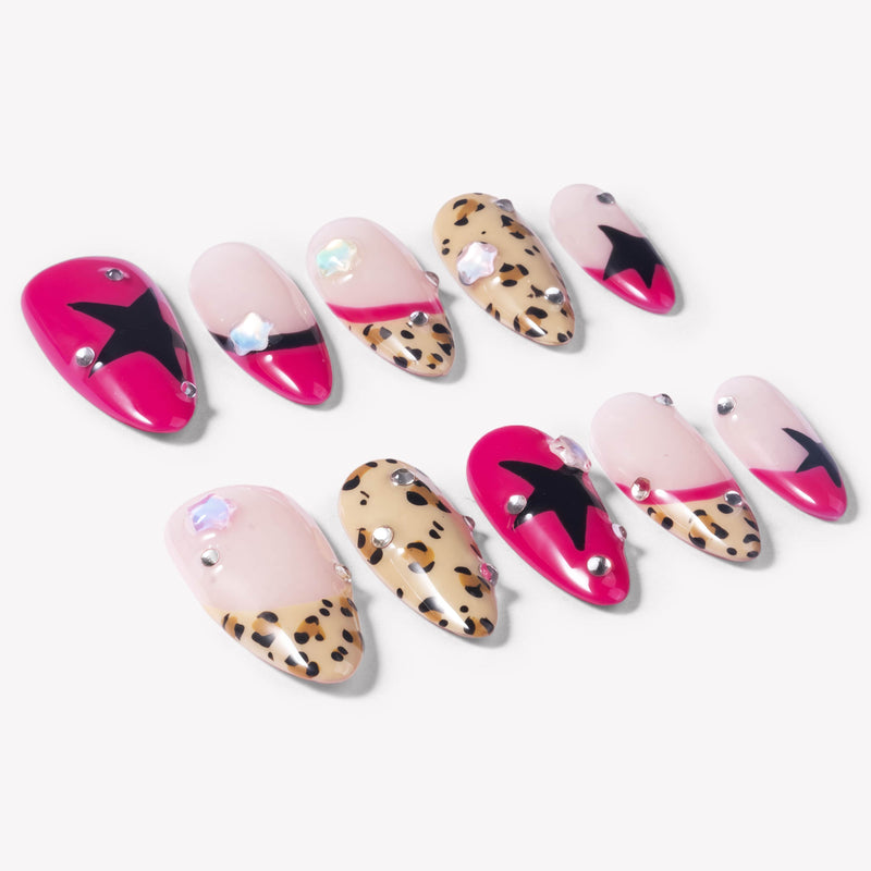 Flat lay of Pop Punk press-on nails with hot pink tips, leopard print accents, black star designs, and small rhinestones