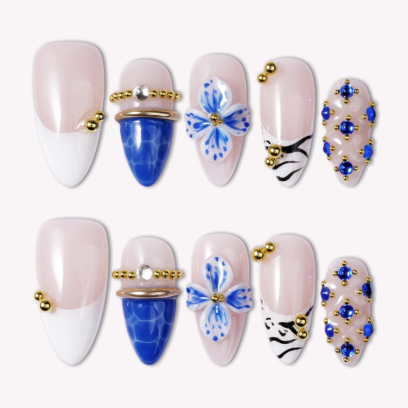 Porcelain Azure handmade press-on nails in nude and cobalt blue with gold bead accents, arranged on a white background.