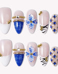 Porcelain Azure handmade press-on nails in nude and cobalt blue with gold bead accents, arranged on a white background.