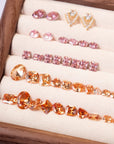Flat lay of precision-cut crystals in pink, gold, and amber tones arranged in a display tray