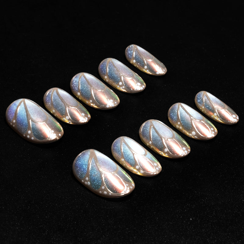 A black background flat lay of iridescent pastel press-on nails with metallic leaf outlines and dotted accents