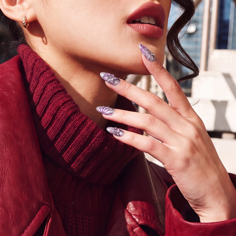 Close-up of Purple Dream lavender floral press-on nails beside a model's lips and red leather jacket