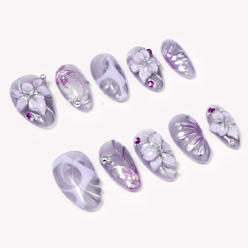 Angled flat lay of Purple Dream lavender floral nails with silver flower details and magenta rhinestones