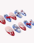Rebel Cherry handmade press-on nails flat lay showing red tips, blue textured nails, silver bows, and cherry charms