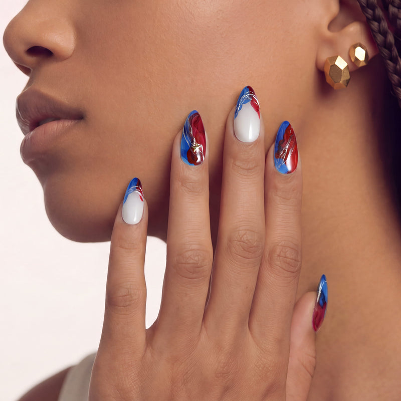 Face close-up of a hand model wearing red, white, and blue press-on nails.