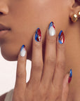 Face close-up of a hand model wearing red, white, and blue press-on nails.