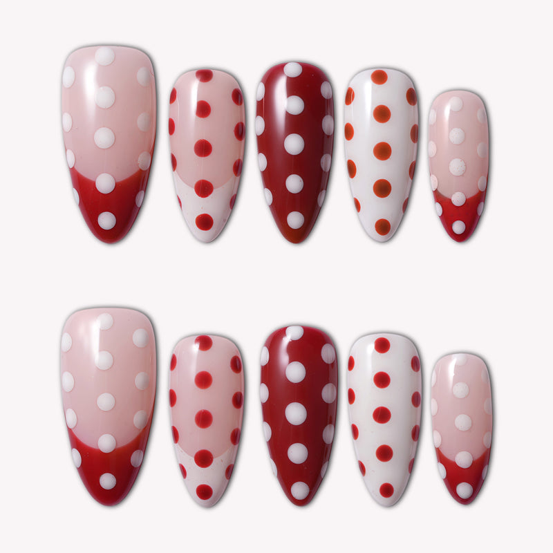 Set of ten almond-shaped press-on nails in retro red and white polka dot pattern with French tips, arranged symmetrically on a plain background
