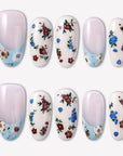 Retro Pastoral press-on nails with pale pink bases, light blue curved tips, gold foil accents, and tiny red and blue floral designs