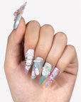 Hand model wearing Rococo Reverie press-on nails with pastel blue and pink bases, 3D roses, pearls, lace details, and bows