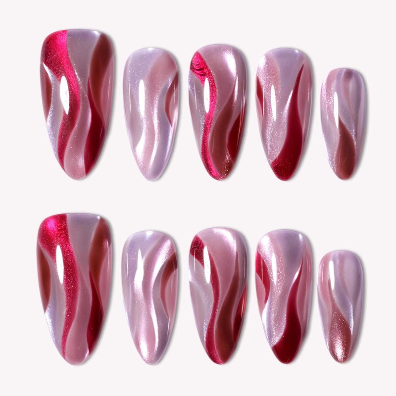 Rose Drift almond press-on nails with burgundy and pink cat eye wave designs arranged in a white background flat lay