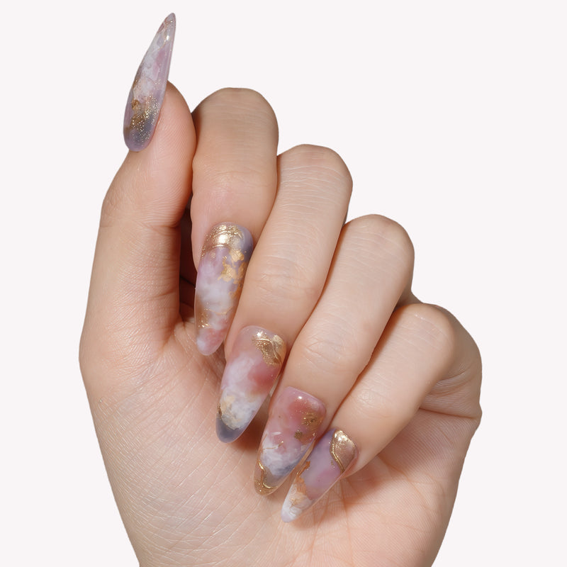 Close-up of a hand wearing Rose Veil Aureate press-on nails in blush pink, ivory, and gold foil