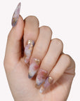 Close-up of a hand wearing Rose Veil Aureate press-on nails in blush pink, ivory, and gold foil