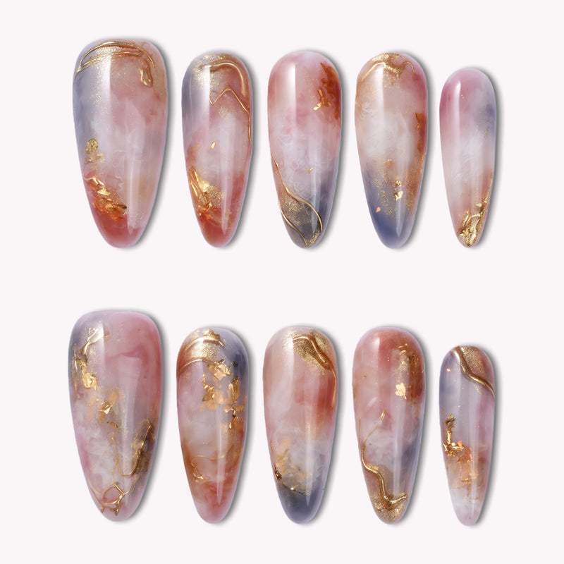 Flat lay of Rose Veil Aureate press-on nails in blush pink, ivory, and gold foil with soft marbled accents
