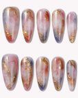 Flat lay of Rose Veil Aureate press-on nails in blush pink, ivory, and gold foil with soft marbled accents