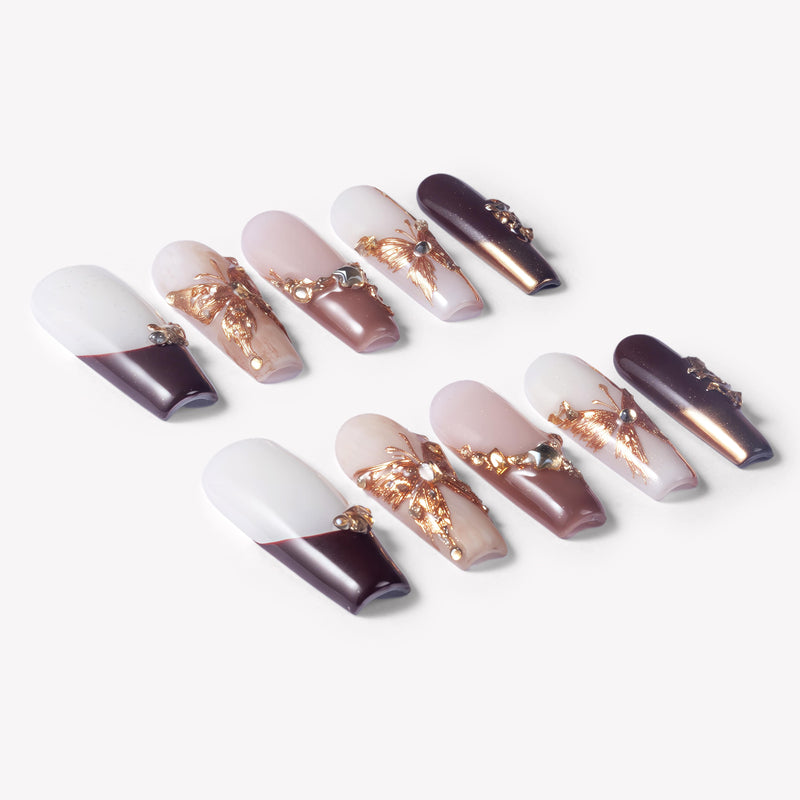 Angled flat lay of Rosegold Flutter press-on nails with burgundy French tips, soft pink accents, rosegold butterfly charms, and rhinestones