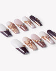 Angled flat lay of Rosegold Flutter press-on nails with burgundy French tips, soft pink accents, rosegold butterfly charms, and rhinestones