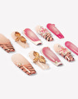 Angled flat lay of Sakura Blaze pink and nude nails with gold flowers, sakura blooms and pearls