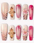 Sakura Blaze pink and nude press-on nails with raised gold flowers, sakura blooms and pearl accents