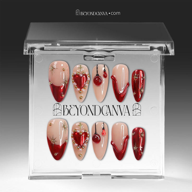 Scarlet Heart Oath press-on nails displayed in clear packaging with nude, deep red, and gold heart, starburst, and bead accents