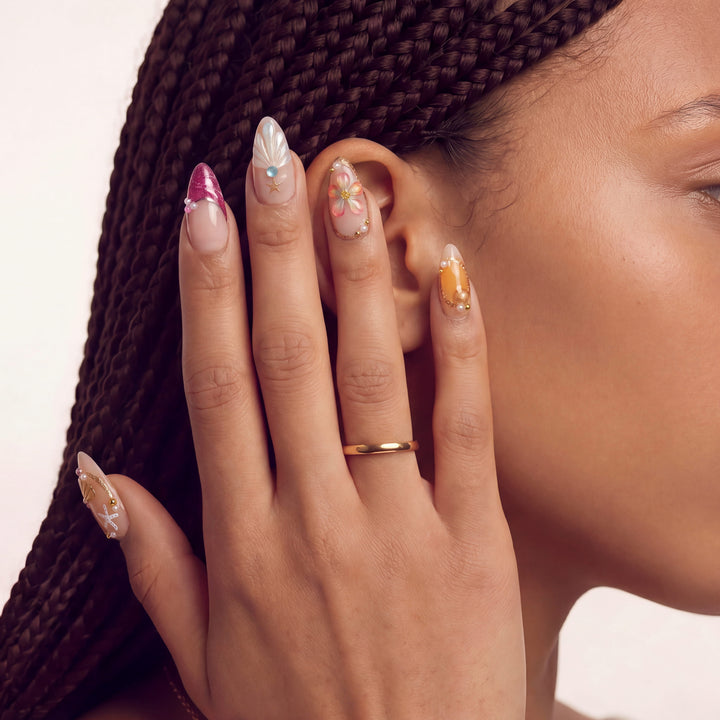 Hand model with braided hair wearing ocean-inspired press-on nails with shell and starfish accents.