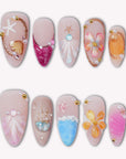 Colorful press-on nails with seashell, starfish, flower, coral, and ocean-inspired details arranged on a white background.