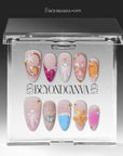 Clear acrylic packaging display showing the ocean-inspired press-on nail set arranged in two rows.