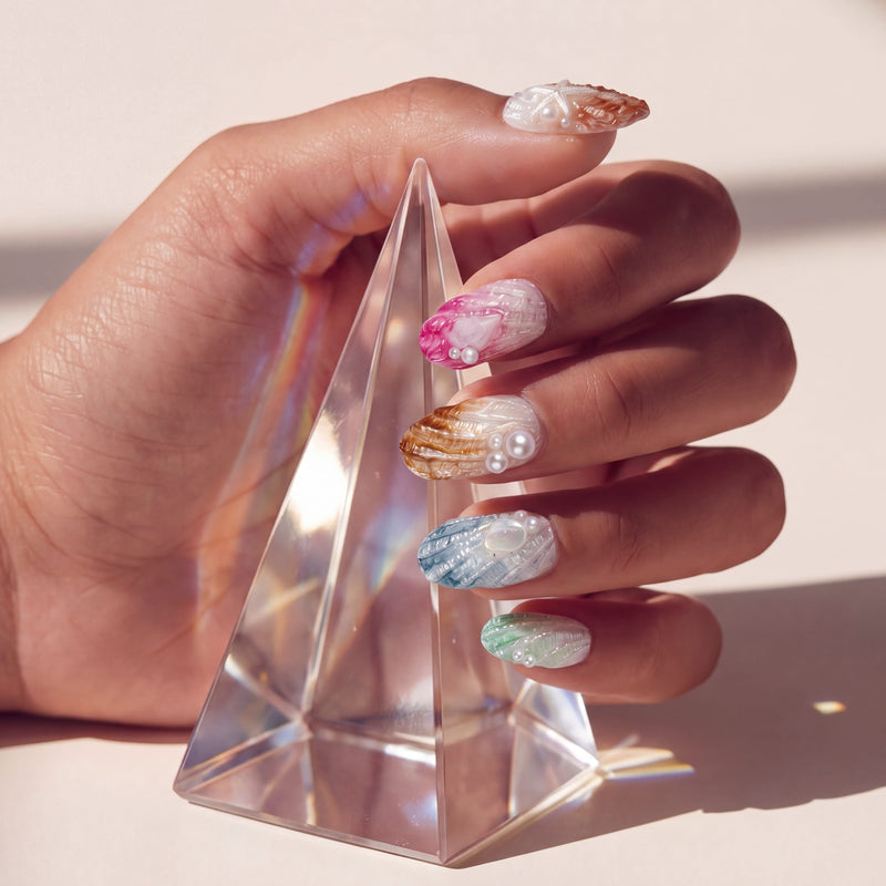 Hand model holding a clear crystal prism while wearing multicolor pearl-textured press-on nails.