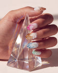 Hand model holding a clear crystal prism while wearing multicolor pearl-textured press-on nails.