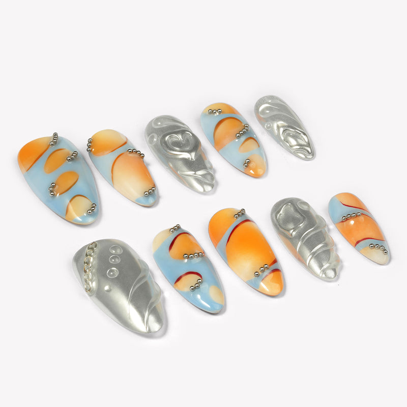 Angled flat lay of Solar Pulse orange, pale blue and silver chrome nails with hearts, swirls and bead details