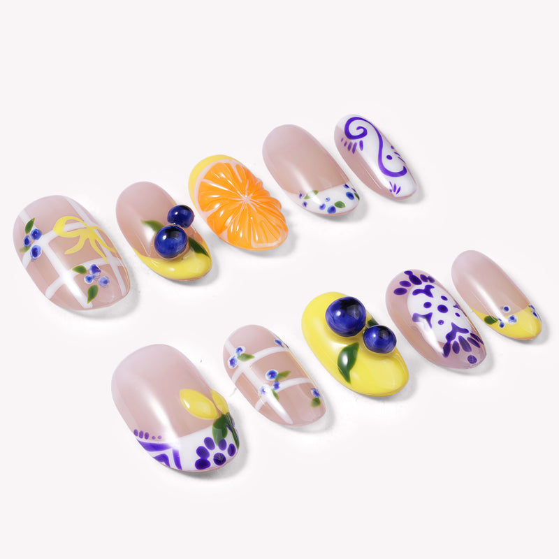 South Holiday press on nail set arranged in a flat lay with colorful floral and fruit-inspired designs on a white background