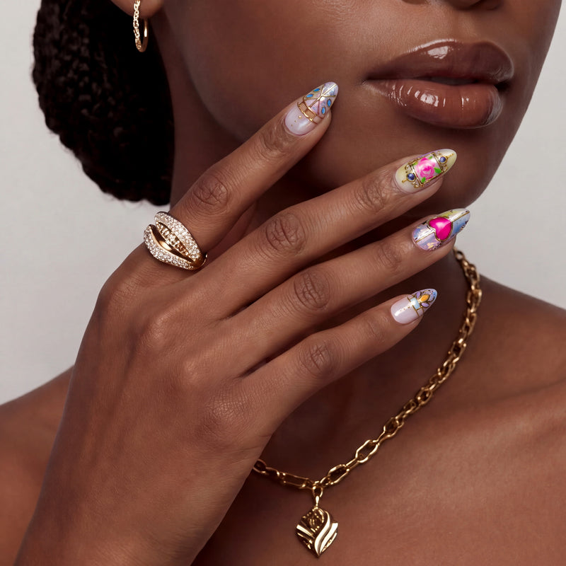 Close-up portrait of a woman wearing colorful stained glass press on nails with gold jewelry