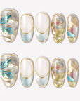 Stained Glass Leaves press-on nails with blue, cream, pink, and green translucent leaf panels, raised gold outlines, and glossy shimmer finish