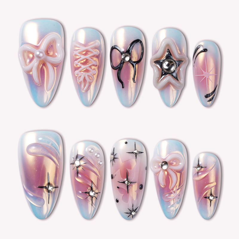 A set of iridescent blue and pink press-on nails with 3D bows, star accents, and rhinestone details on a white background
