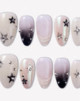 Stellar Muse press-on nails with black and silver star charms, rhinestones, silver beads, glossy nude pink bases, and black gradient accents