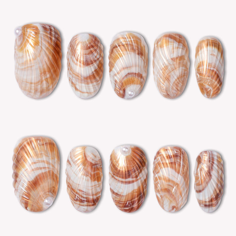 Sunset shell press on nails with warm orange and white shell-inspired swirls arranged in a flat lay on a white background