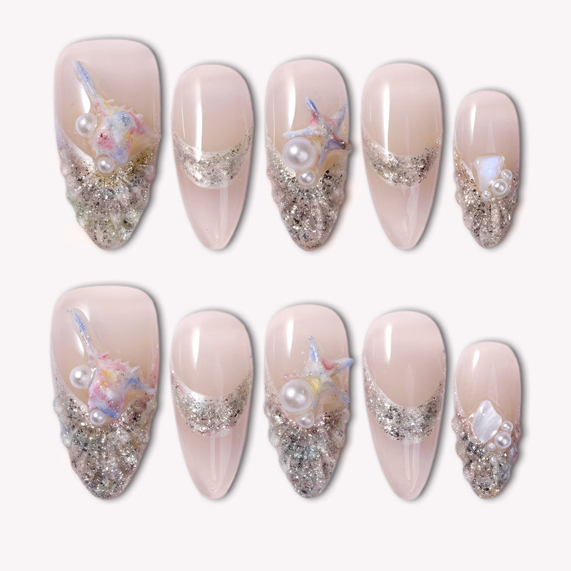 Silver shell-inspired press-on nails with pearl and starfish details arranged in two rows on a white background.