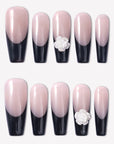Timeless Serenity press-on nails with glossy nude bases, black French tips, subtle shimmer, and white 3D flower accents arranged in a full set