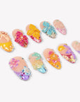 Angled flat lay of Tropical Bloom colorful press-on nails with raised tropical flowers, shells and gems