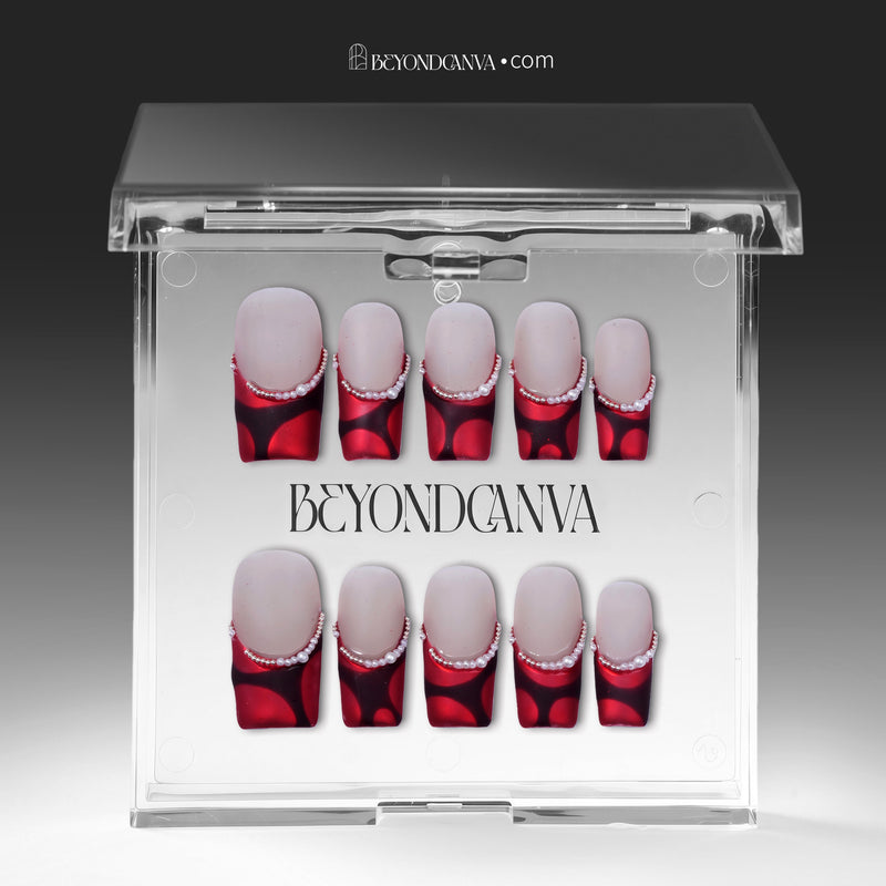 Vintage Ruby press-on nails displayed in clear packaging with glossy red and black bases and pearl accents