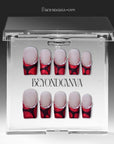 Vintage Ruby press-on nails displayed in clear packaging with glossy red and black bases and pearl accents