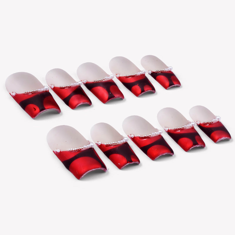Flat lay of Vintage Ruby press-on nail swatches with red marbled bases and pearl accents