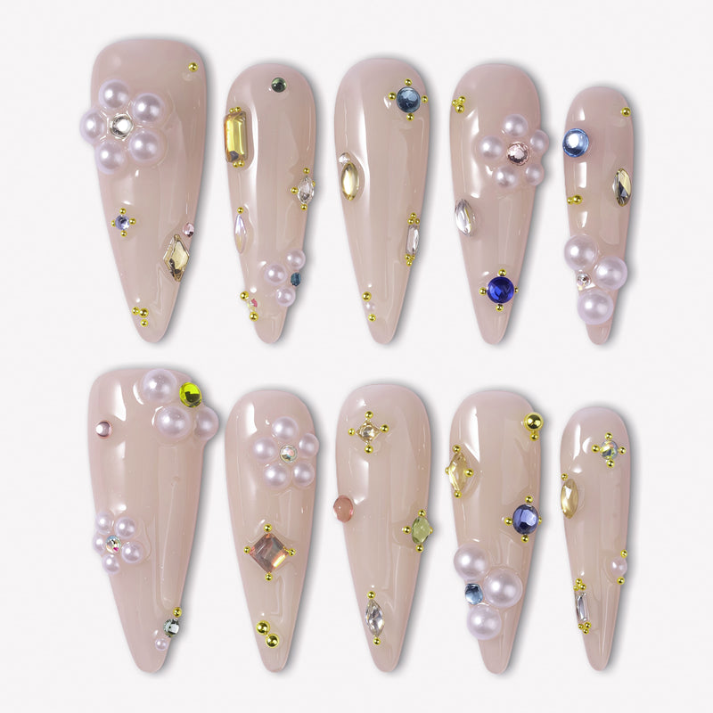 Water Drop Shimmer press-on nails with nude almond bases, pearl clusters, colorful gem accents, and tiny gold bead details