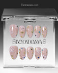 Press-on nails displayed inside a clear BeyondCanva case with nude pink stiletto nails, pearl clusters, and gold accents