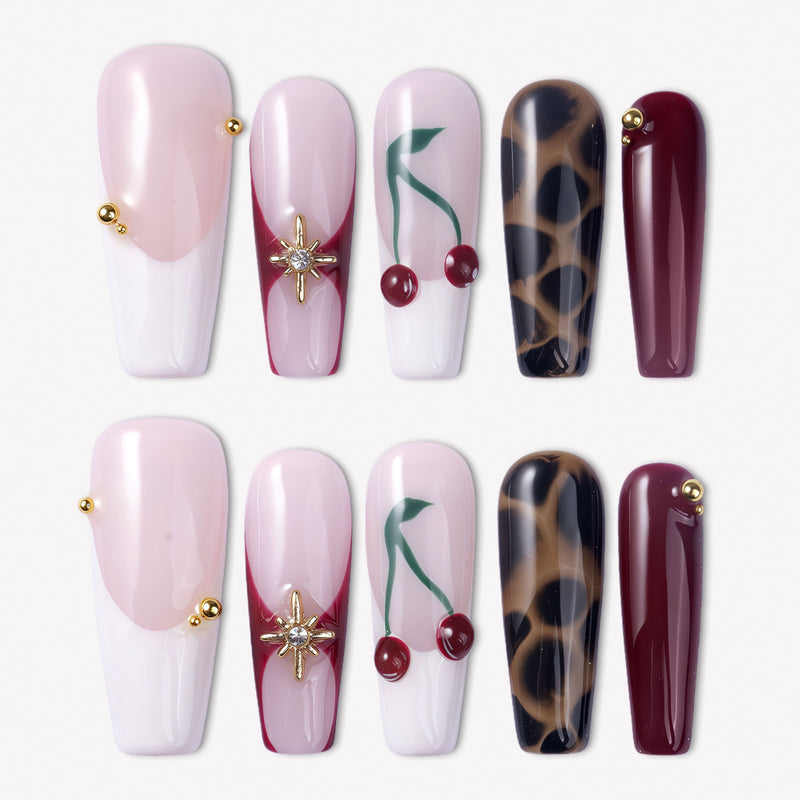 Wild Cherry press-on nails with pink sheer bases, burgundy accents, cherry art, leopard print, and gold embellishments