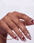 Close-up of a hand model wearing red and white marble press-on nails