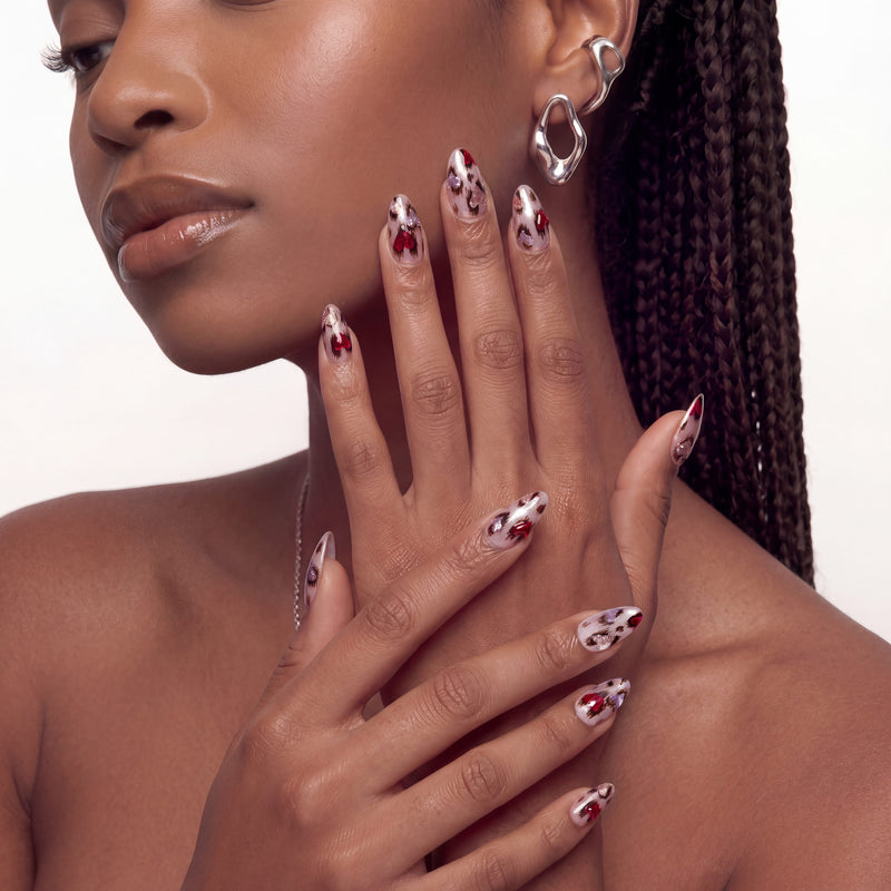 A hand model wearing red and white marble press-on nails