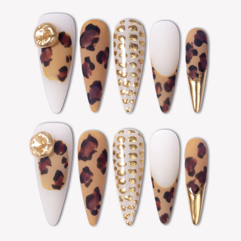 Wild Majesty press-on nails with tan leopard print, white bases, raised gold dot accents, gold charms, and metallic gold stiletto tips